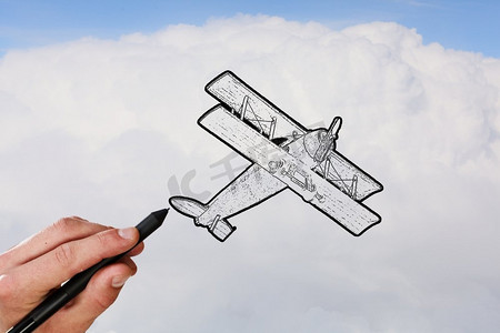 手绘平面摄影照片_双平面草图。在天空背景上手绘旧飞机的人