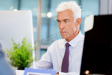 坐在办公室里用电脑工作的商人。又一个在电脑前办公的日子