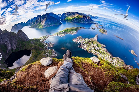 第一人称视角,一位徒步旅行者坐在罗弗敦 (lofoten) 悬崖边,是挪威
