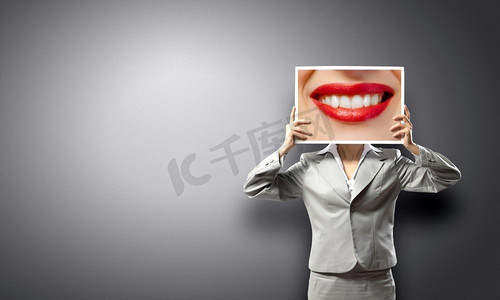 拿着照片摄影照片_一位展示照片的女士。面目全非的女商人拿着大嘴唇的大照片