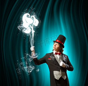 巫师摄影照片_戴帽子的魔术师。男子魔术师在彩色背景下表演魔术的形象