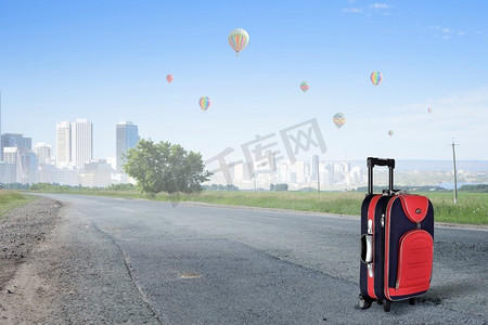 红色行李箱在路上旅行概念与红色手提箱在路上
