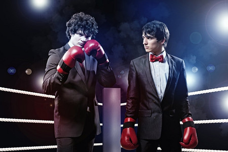 两个年轻的商人在打拳击。两个年轻的商人在黑暗的背景下打拳。概念拼贴