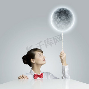 月球星球摄影照片_有月亮的女人。年轻女子手持月球星球颜色的气球