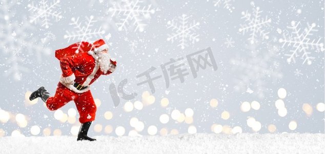 游戏礼包盒摄影照片_圣诞送货高峰。圣诞老人带着装满礼物的礼包在雪地上奔跑着迎接新年或圣诞节的送货高峰