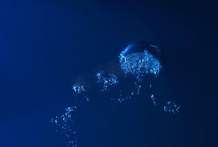 深蓝色蓝色摄影照片_水花飞溅。清澈的蓝色水在深蓝色的背景上飞溅