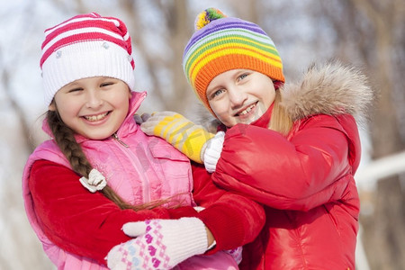两个可爱的女孩在冬季公园玩得开心。冬季活动
