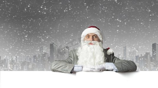 圣诞指向牌摄影照片_圣诞老人与横幅商人在圣诞老人帽子与白色空白横幅