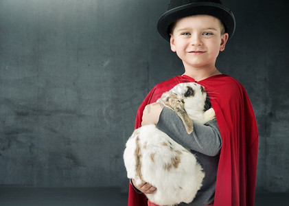兔子魔术师摄影照片_小魔术师抱着一只神奇的兔子