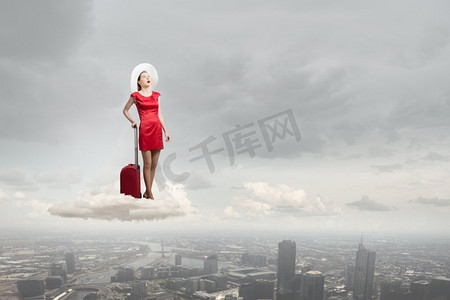 行李箱红色摄影照片_穿红衣服的女人。年轻动情的女人穿着红色连衣裙，背着红色行李箱