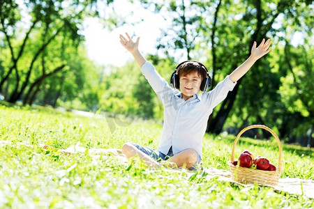 夏日公园里戴着耳机的快乐小男孩。天籁之声