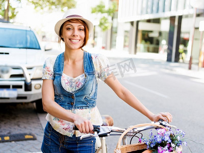 女子骑马摄影照片_骑自行车的美女。美丽的年轻女子在城市里骑自行车