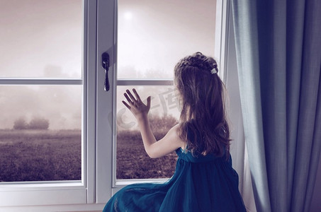 孤独的孩子摄影照片_可怜的孩子看着窗外