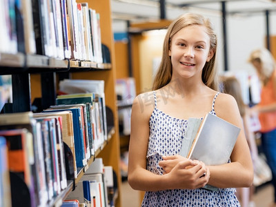 十几岁的女孩在公共图书馆挑选一本书。这是一个艰难的选择
