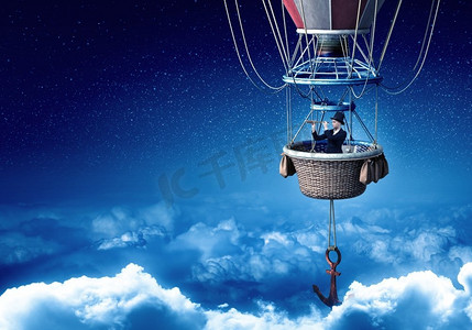 浮空器摄影照片_乘坐浮空器旅行的女子。年轻的女商人戴着五颜六色的浮空器在天空中飞翔