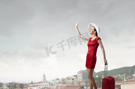 穿红衣服的女人。年轻女子在红色礼服与红色行李打手势用手