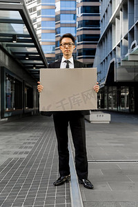 一名商人在城市街道上举着一条空白的横幅。阅读我的消息