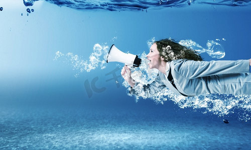 晶莹剔透摄影照片_一名女子在水中。穿着西装的年轻女商人在晶莹剔透的碧水中游泳