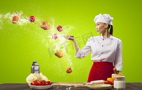 亚裔女厨师用刀做饭。亚洲女厨师在空中用刀切水果和蔬菜