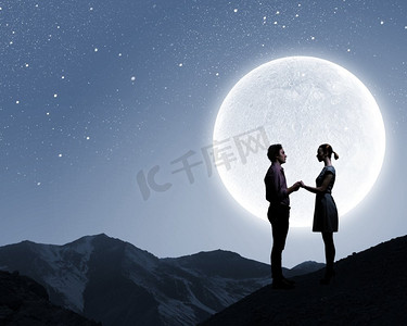 背景大月亮映衬下的情侣剪影