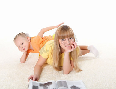 母亲读书摄影照片_年轻的母亲在地毯上给她的小女儿读书