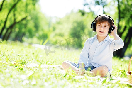 中国医生之声摄影照片_夏日公园里戴着耳机的快乐小男孩。天籁之声