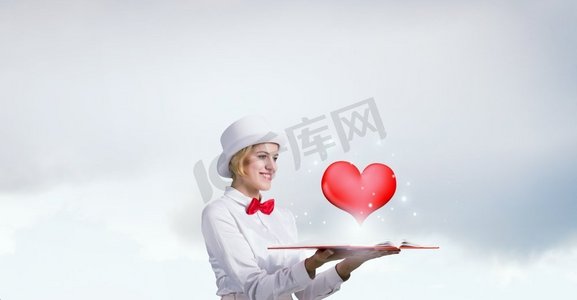 美女开启浪漫之书。年轻女子穿着白色圆柱体，打着红色领结，手里拿着书