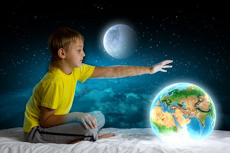 夜里做梦。可爱的男孩坐在床上做梦。这张图片的要素由美国宇航局提供
