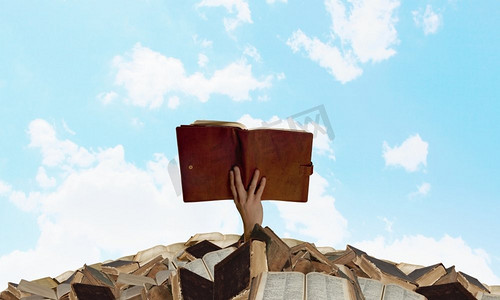 找到你的书。手拿着书从一堆旧书中伸出来