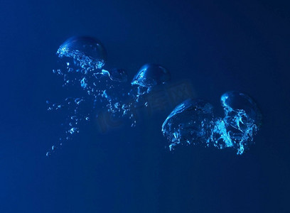 水花飞溅。清澈的蓝色水在深蓝色的背景上飞溅