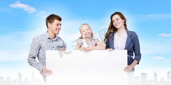 年轻的家庭。幸福的一家三口举着白色的空白横幅。文本位置