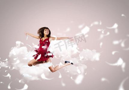 跳跃的女人。年轻漂亮的红裙女子跳得很高