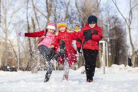 可爱的孩子跳跃和具有乐趣在冬季公园。冬季活动