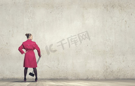 红衣女子背影摄影照片_拿着锤子的女人。手持锤子的红衣女子的背影