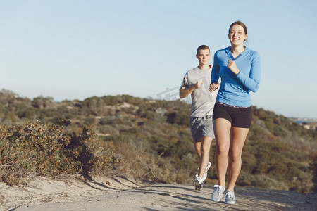 体育跑步者在海滩慢跑锻炼出与她的伙伴.适合女性健身模型慢跑沿着海洋与她的伙伴