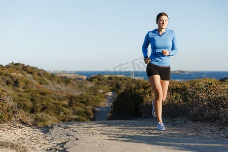 体育跑步者慢跑在海滩锻炼出来。适合女性健身模型慢跑沿海洋