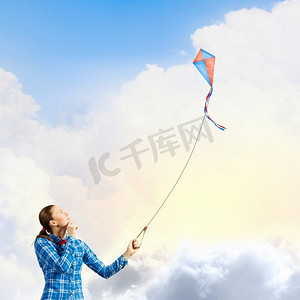 风筝玩具摄影照片_户外运动。穿着休闲服装的年轻女子玩着五颜六色的风筝