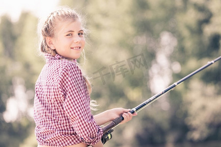 肖像可爱的女孩坐在银行和钓鱼