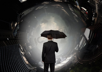 撑伞背影摄影照片_撑着伞的商人。打着伞看着城市的商人的背影