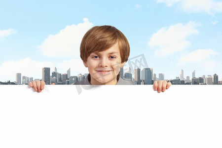拿着一块空白广告牌的男孩。一个小男孩拿着一块空白的白色广告牌