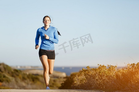 体育跑步者慢跑在海滩锻炼出来。适合女性健身模型慢跑沿海洋