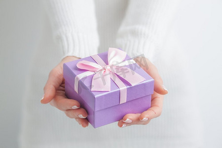 618紫色主图摄影照片_拿着礼物的女人。一名女子手里拿着紫色小礼盒
