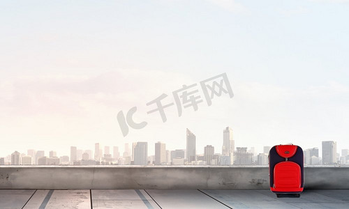 假期旅行行李箱摄影照片_红色行李箱在路上。红色行李箱上路的旅行理念