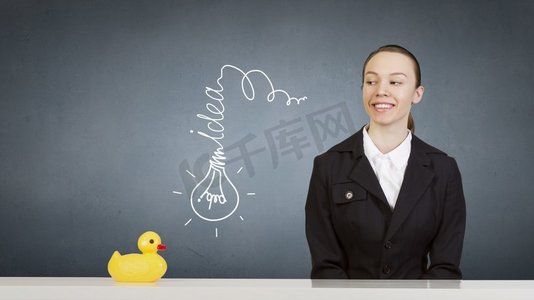 套鸭子摄影照片_女人与鸭子玩具。年轻的女商人和黄色橡胶鸭玩具在桌子上