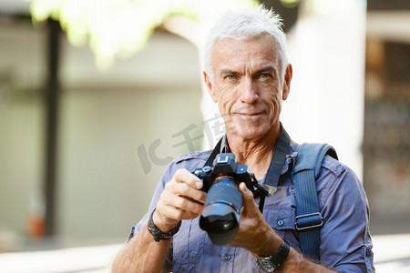 在城市里拿着相机的老年男子。寻找好的萌芽