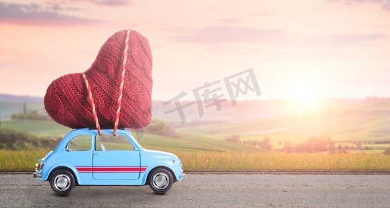 蓝色复古玩具车提供心脏情人节反对模糊的农村托斯卡纳日落景观