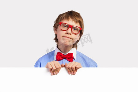 戴着红色眼镜的学生拿着白色的正方形。图像困惑的男孩举行白色广场。广告位
