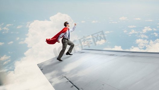 飞超人摄影照片_他飞得很高。站在机翼边缘的超人