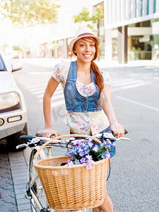 女子骑马摄影照片_骑自行车的美女。美丽的年轻女子在城市里骑自行车