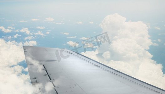 飞机机翼伸出窗外。飞行飞机从照明器在蓝天